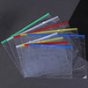 A collection of transparent plastic pockets and dividers with colored strips are arranged diagonally on a dark surface.