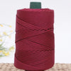 A spool of deep red crochet ice rope with a dark green cap, resting on a woven mat.