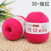 A ball of bright pink yarn labeled as Red Silk Yarn for knitting and crochet resting on a woven mat.