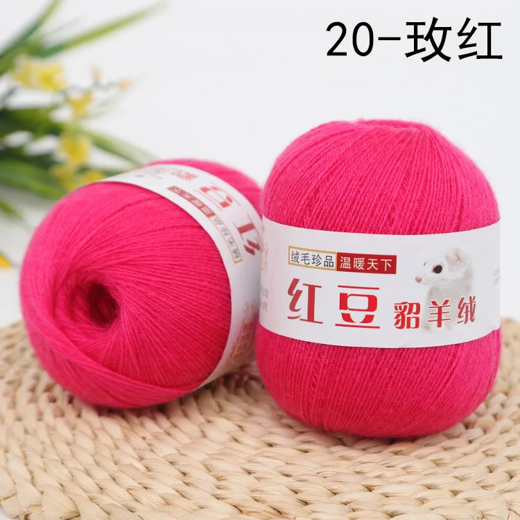 A ball of bright pink yarn labeled as Red Silk Yarn for knitting and crochet resting on a woven mat.