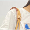 A close-up of a light pink leather handbag handle wrap and shoulder pad on a white sleeve.