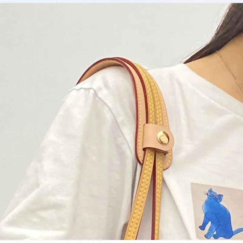 A close-up of a light pink leather handbag handle wrap and shoulder pad on a white sleeve.