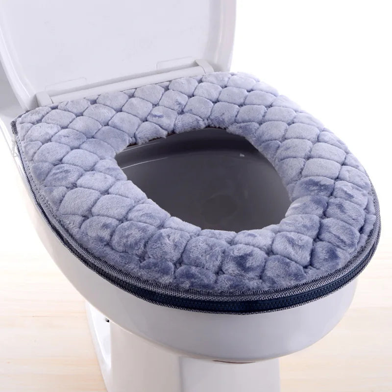 Una cubierta de asiento de inodoro impermeable gris y mullida instalada en una taza de inodoro blanca.
