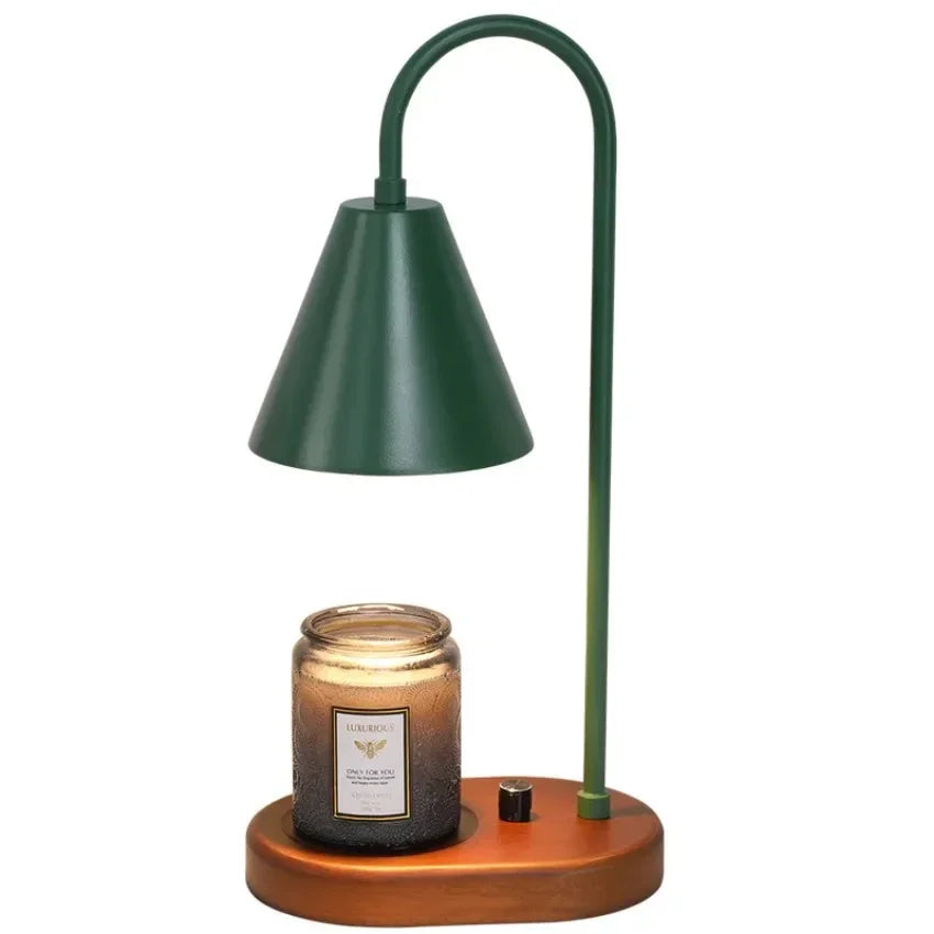 A dark green electric candle warmer lamp with a curved metal arm and a wooden base.