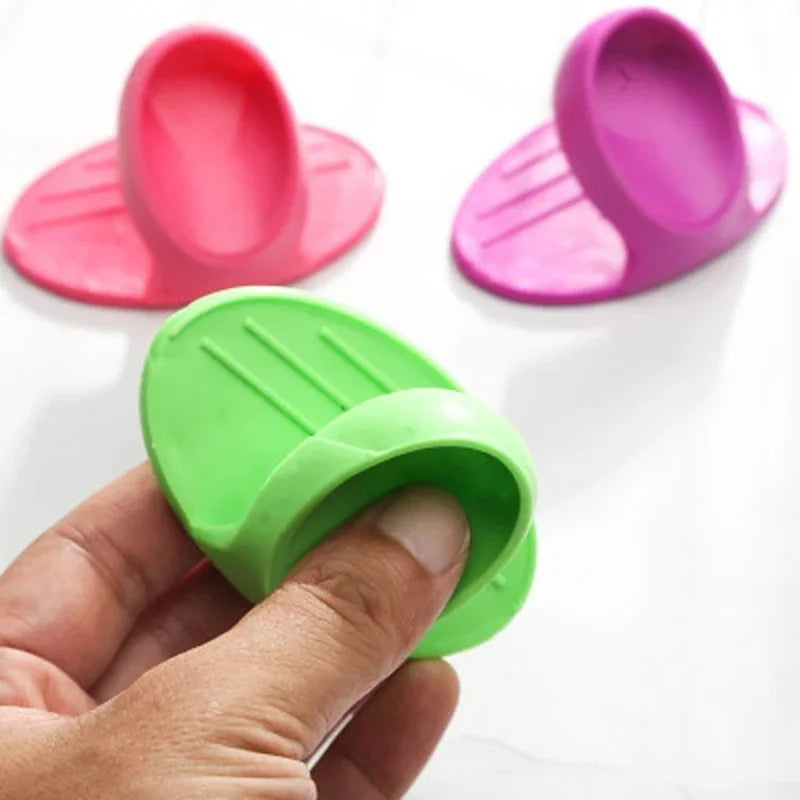 Three silicone finger covers in pink and green colors are shown, with one being held by a hand.