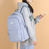 A person is holding a light purple waterproof nylon laptop backpack with gray hoodie and jeans.