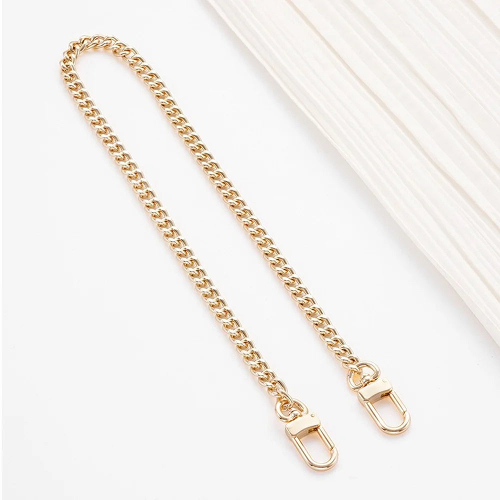 A delicate gold-tone metal chain with hinged buckles used as a purse strap replacement.
