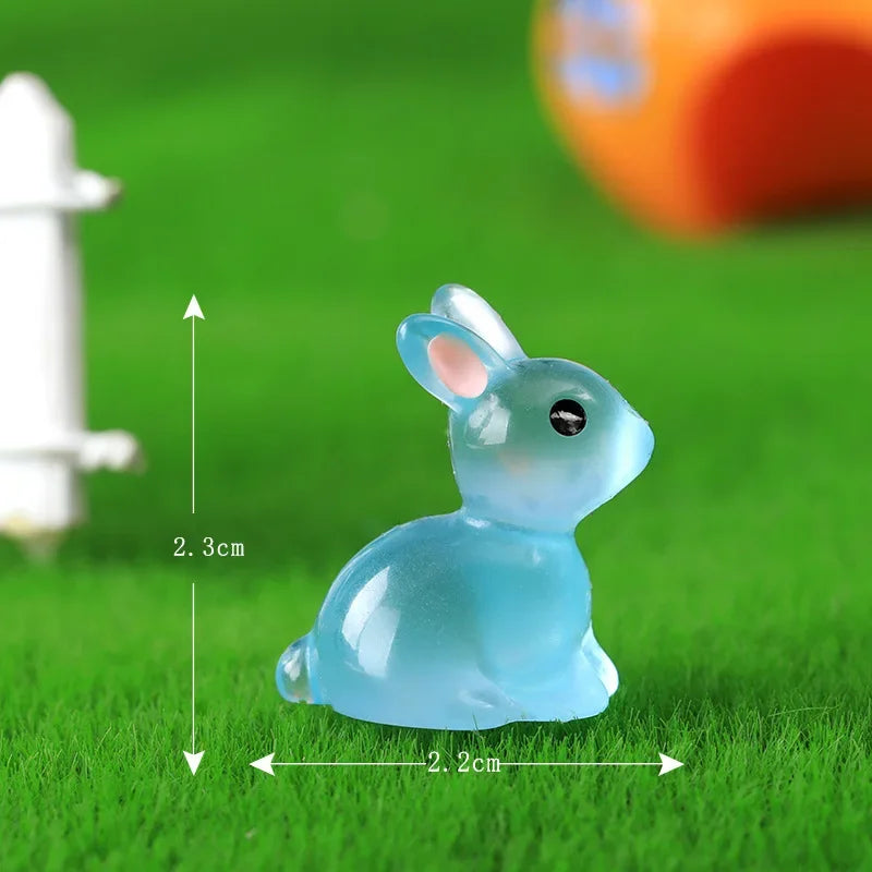 A light blue resin miniature bunny figurine sitting on green grass.