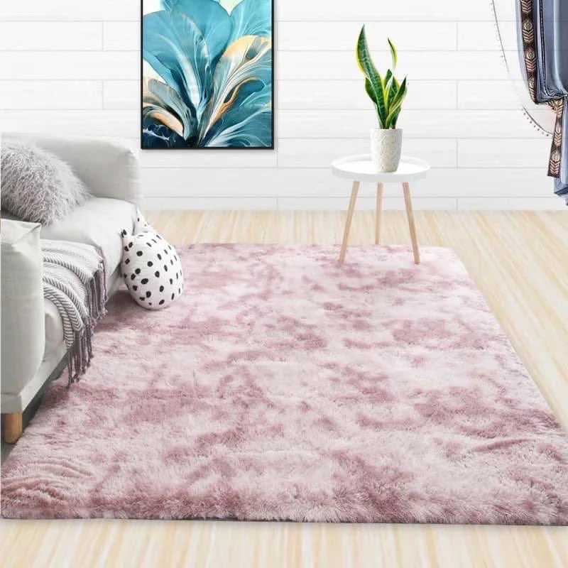 A fluffy pink velvet carpet placed in a living room with a sofa and a plant on a side table.