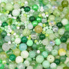 A close-up view of mixed sizes glass beads in various shades of green and white for jewelry making