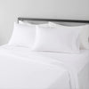 White microfiber bed sheet set with pillows and a dark headboard in a hotel luxury setting