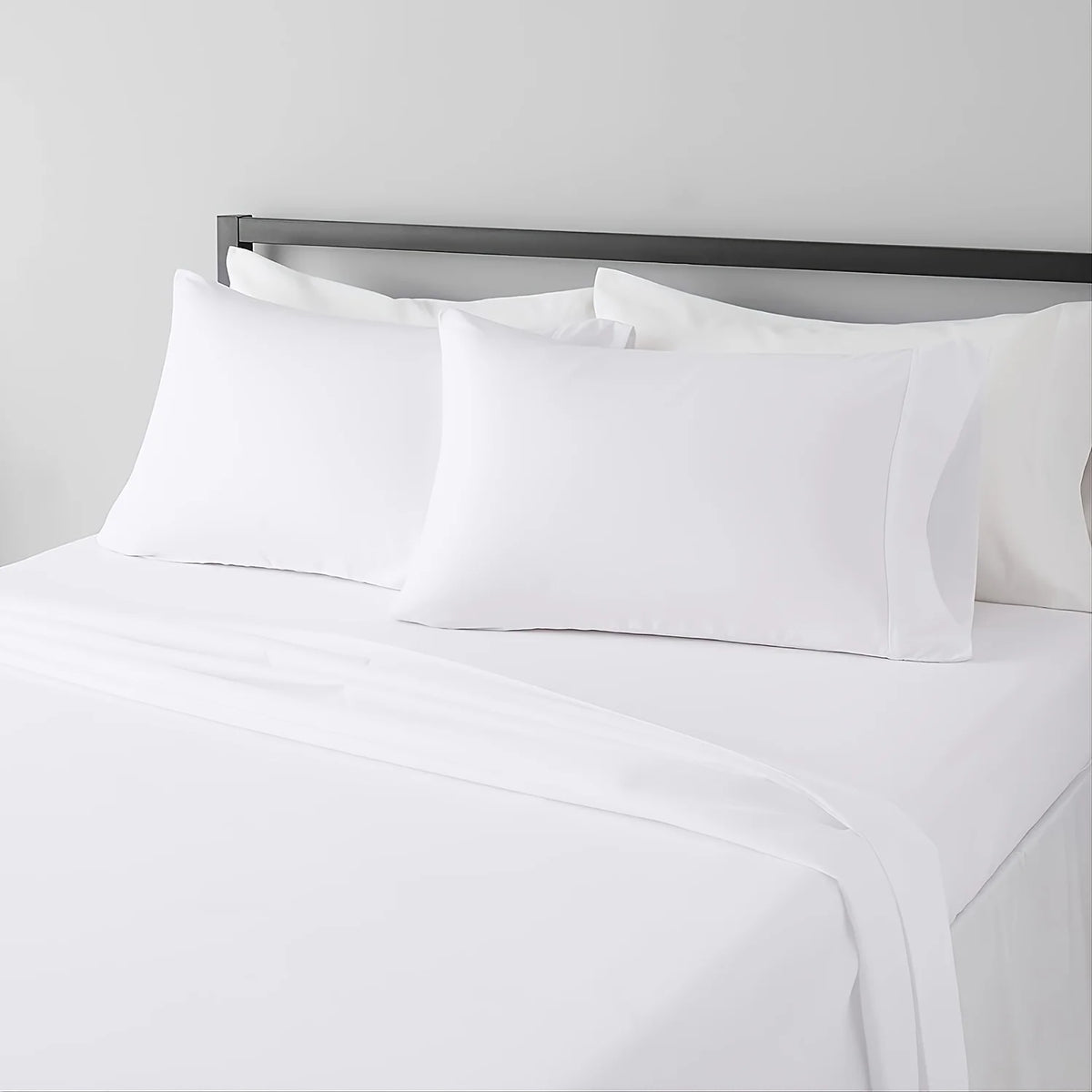 White microfiber bed sheet set with pillows and a dark headboard in a hotel luxury setting
