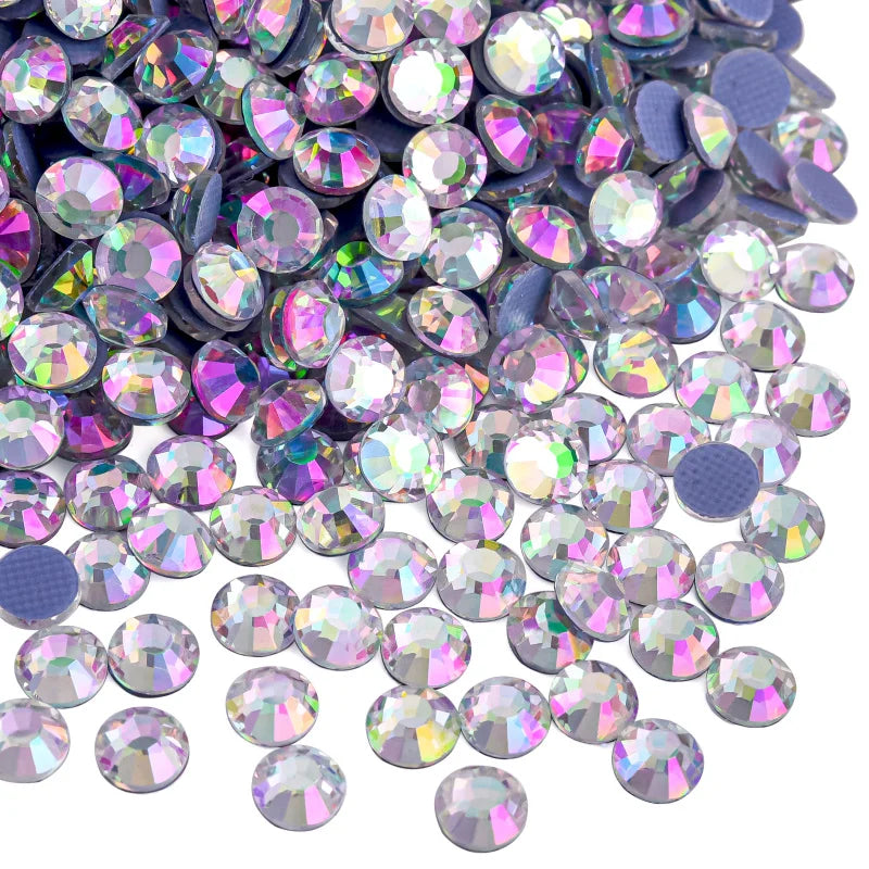 A close-up view of various iridescent and holographic rhinestones in purple, silver, and pink shades.