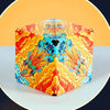 A colorful magnetic fidget cube with a vibrant orange and yellow floral design is shown on a light surface.