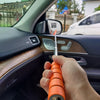 A hand holds an orange telescopic window cleaning squeegee with an adjustable handle inside a car interior.