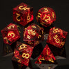 A collection of red resin polyhedral dice, including d6s and d12s, resting on a dark surface.