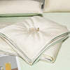 White and mint green ice silk quilt folded on a light green surface.