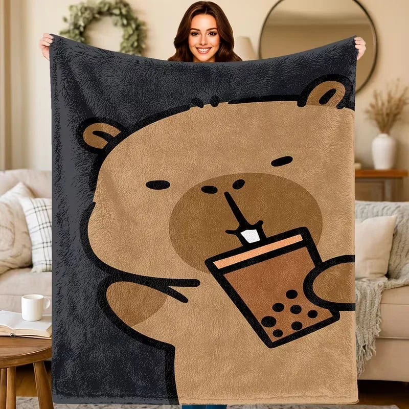 A cartoon bear design on a dark gray flannel throw blanket, holding a coffee cup.