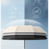 A beige and black automatic folding umbrella is shown open against a light blue sky with rain falling.