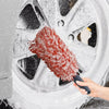 A hand is using a red plush wheel cleaning brush to clean a white car wheel.