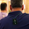 A man wearing a dark blue shirt displays a green scapular necklace with Saint Jude and Our Lady of Guadalupe.