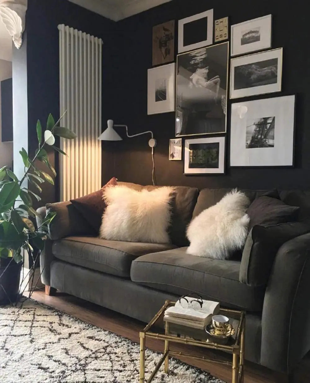 A dark gray sofa in a modern living room decorated with framed art and fluffy pillows.