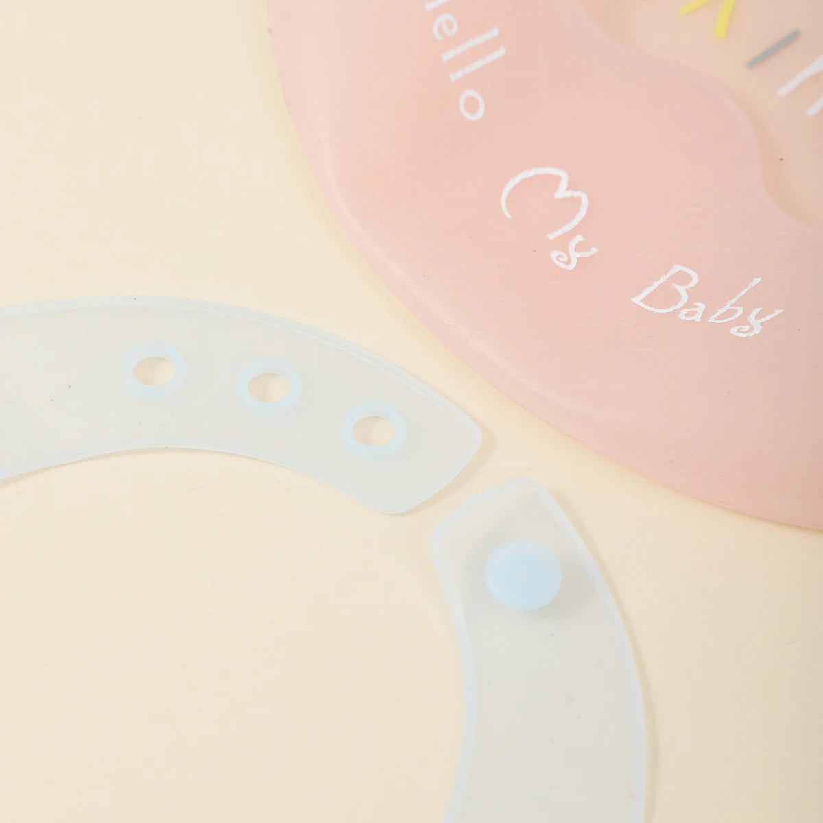A pink silicone baby bib with the text My Baby and a white silicone teething ring.