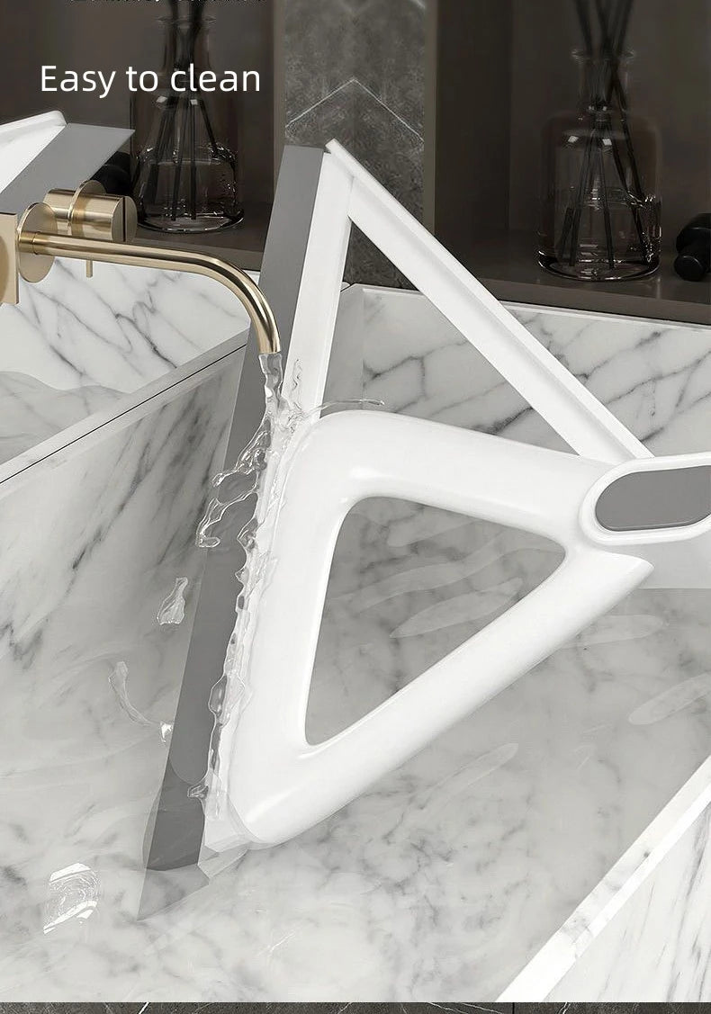 A white silicone squeegee broom is shown cleaning a marble countertop with a gold-toned faucet.