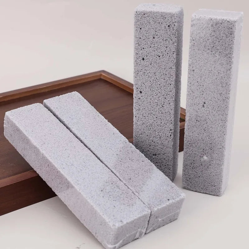 Three rectangular gray pumice stone cleaning sticks are displayed on a wooden tray.