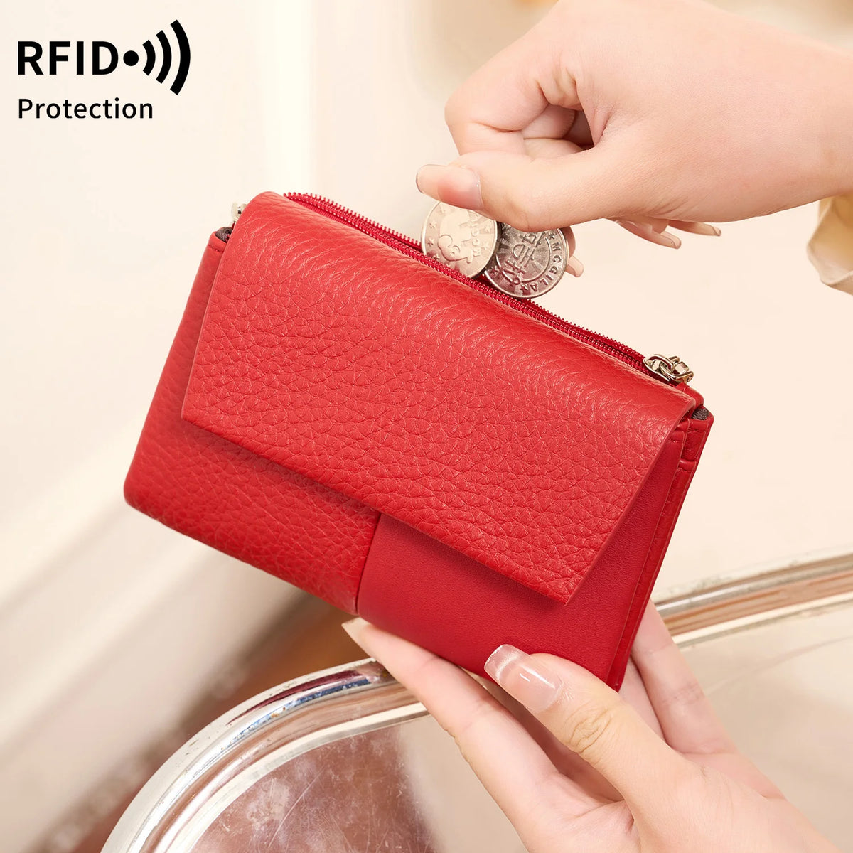 A red tri-fold wallet with a zipper and coin pocket is being held by a hand, demonstrating RFID protection.