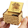A wooden music box with a lid featuring an eagle design and decorative carving, held in a hand.
