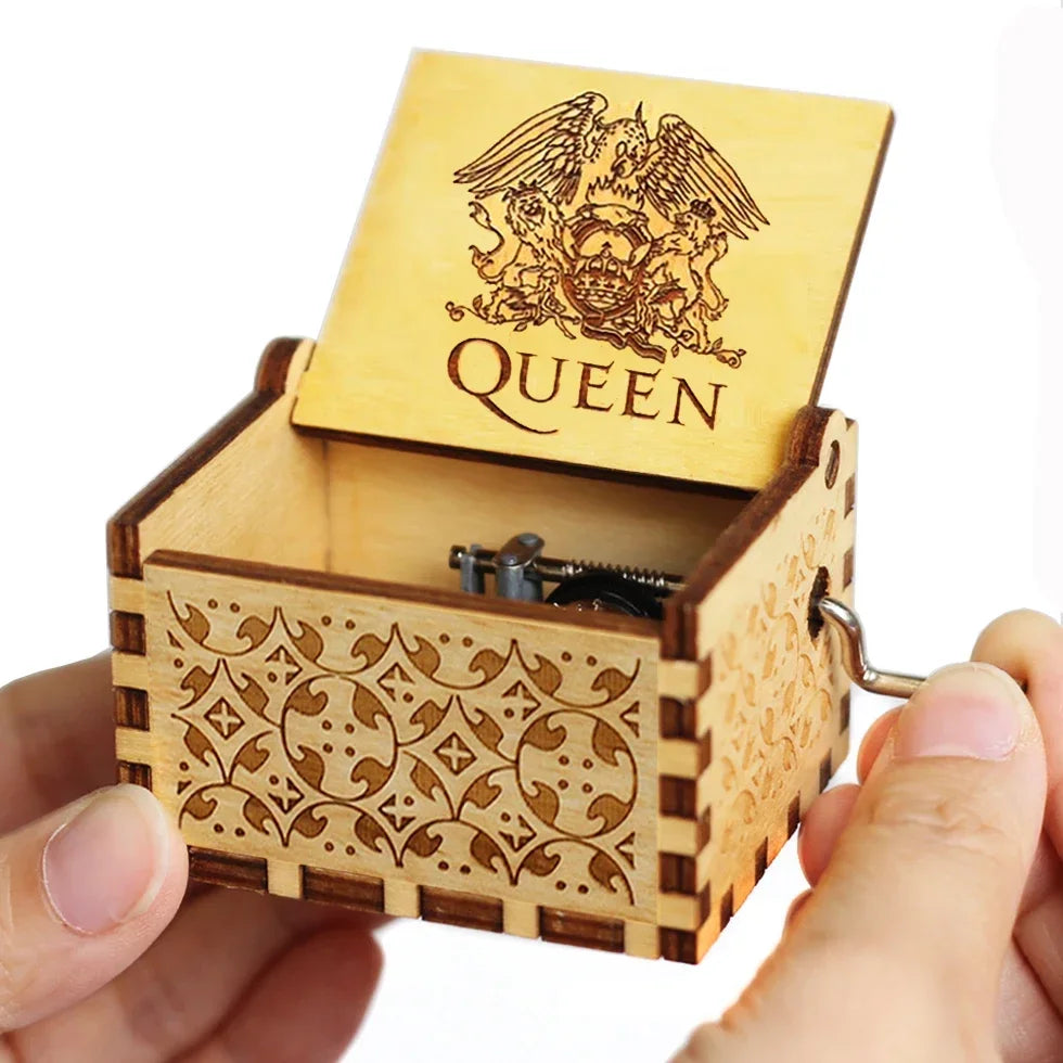 A wooden music box with a lid featuring an eagle design and decorative carving, held in a hand.