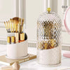 Organizador esférico transparente para brochas de maquillaje con tapa dorada y base blanca.