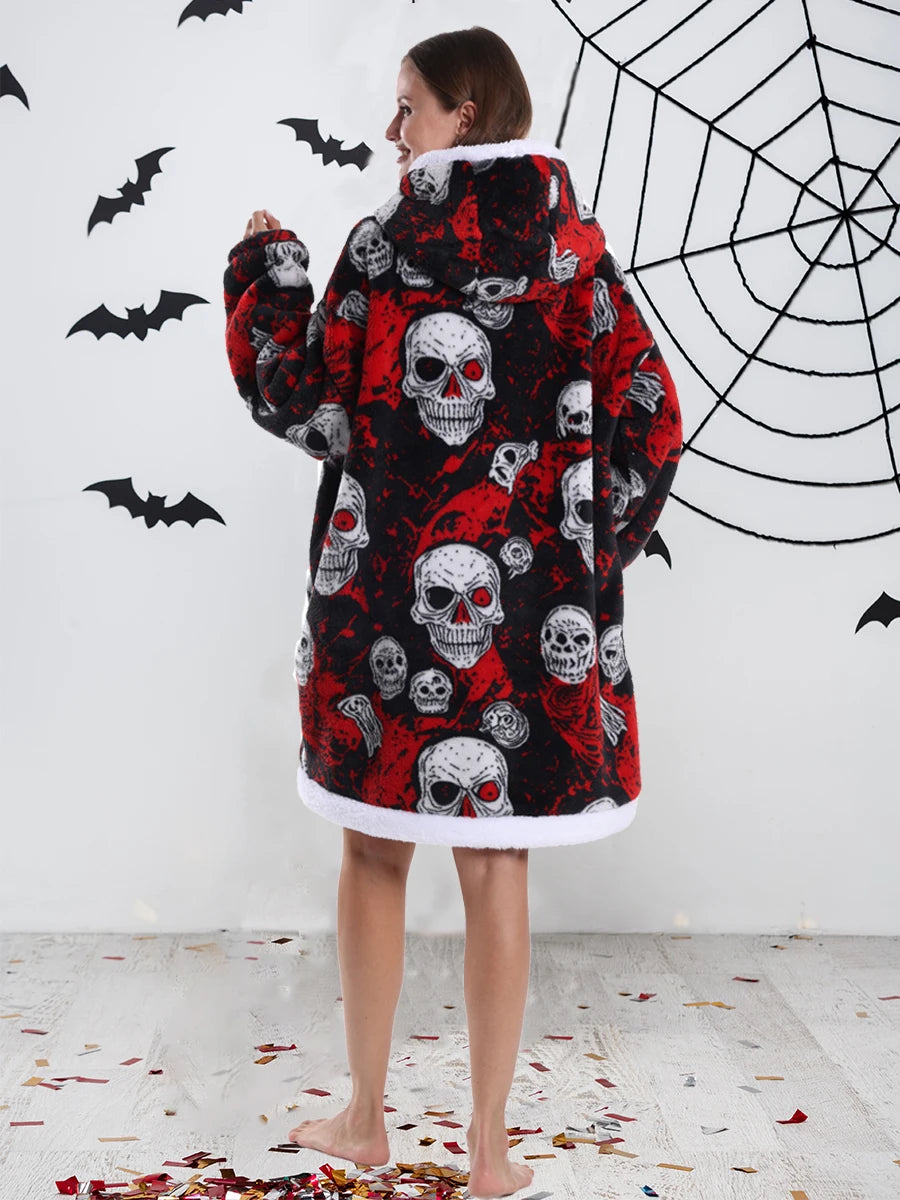 Eine Frau trägt einen rot-schwarz karierten Fleece-Hoodie mit Totenköpfen, steht vor einer weißen Wand mit einer Spinne