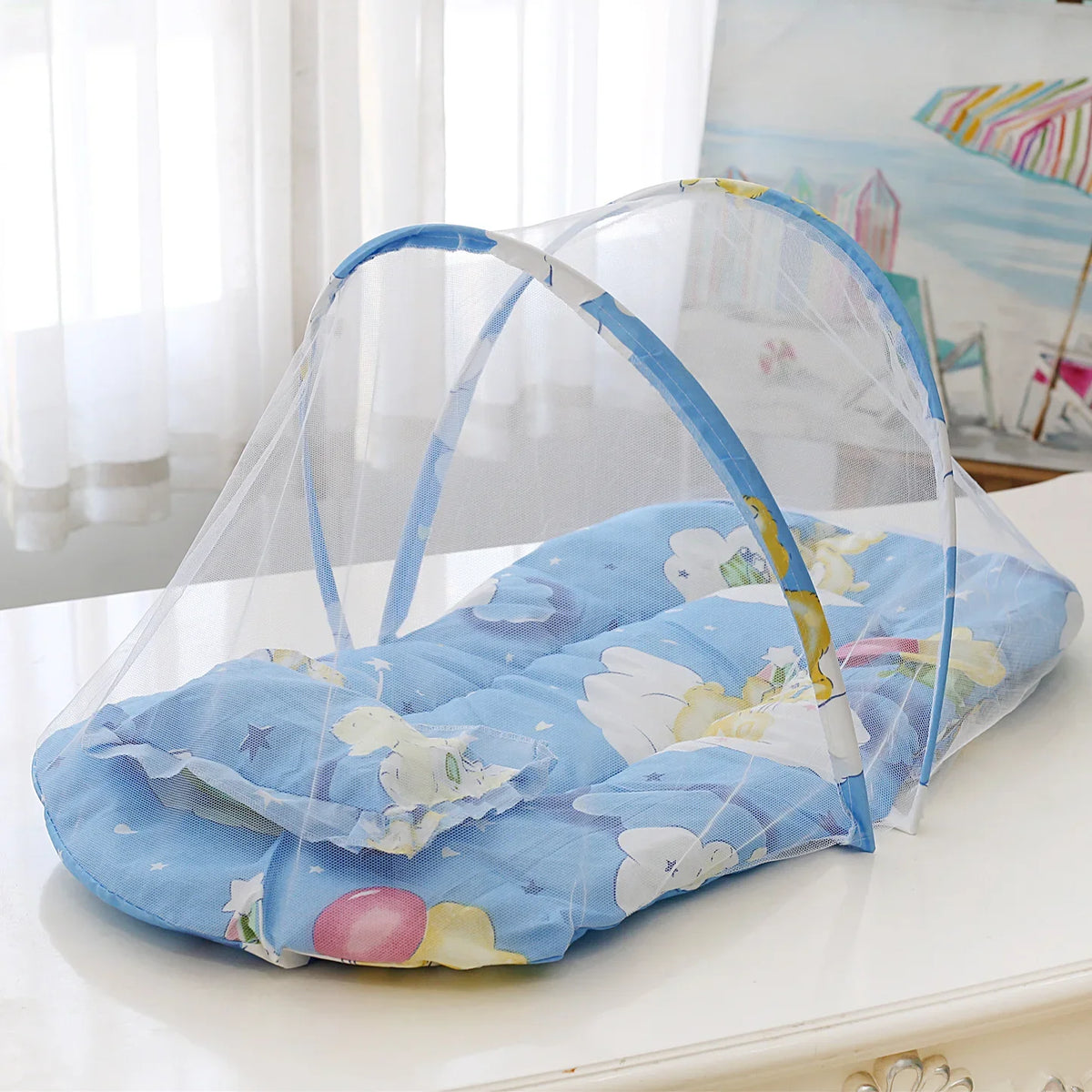 A portable crib mosquito net with a pillow and cotton pad is displayed on a white surface.