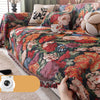 A richly colored floral jacquard sofa blanket with tassels draped over a sofa.