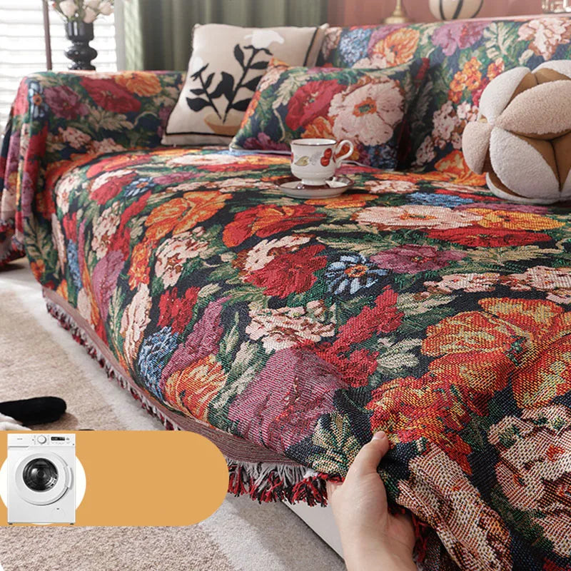 A richly colored floral jacquard sofa blanket with tassels draped over a sofa.