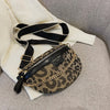 Schwarze und goldene Leopardenmuster-Crossbodytasche vor weißem Stoffhintergrund