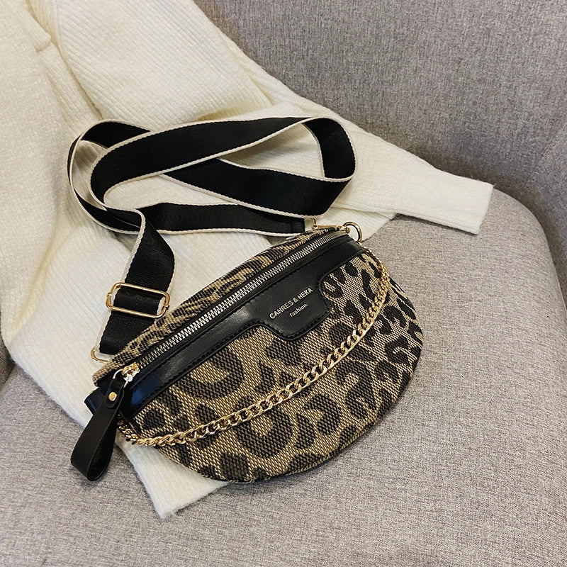 Schwarze und goldene Leopardenmuster-Crossbodytasche vor weißem Stoffhintergrund