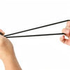 Hands holding two black elastic tent tie-down ropes with plastic buckles.
