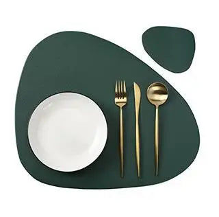 A set of gold-colored cutlery and a white plate are displayed on a dark green placemat.