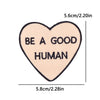 A light pink heart shaped patch embroidered with the text BE A GOOD HUMAN