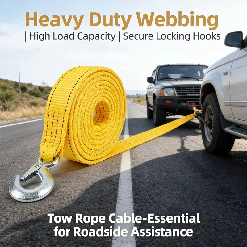 Yellow heavy duty webbing tow rope with metal hooks lying on asphalt next to a pickup truck.