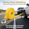Yellow heavy duty webbing tow rope with metal hooks lying on asphalt next to a pickup truck.