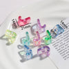 A collection of pink and clear acrylic alphabet beads displayed on a white plate with measurement lines.