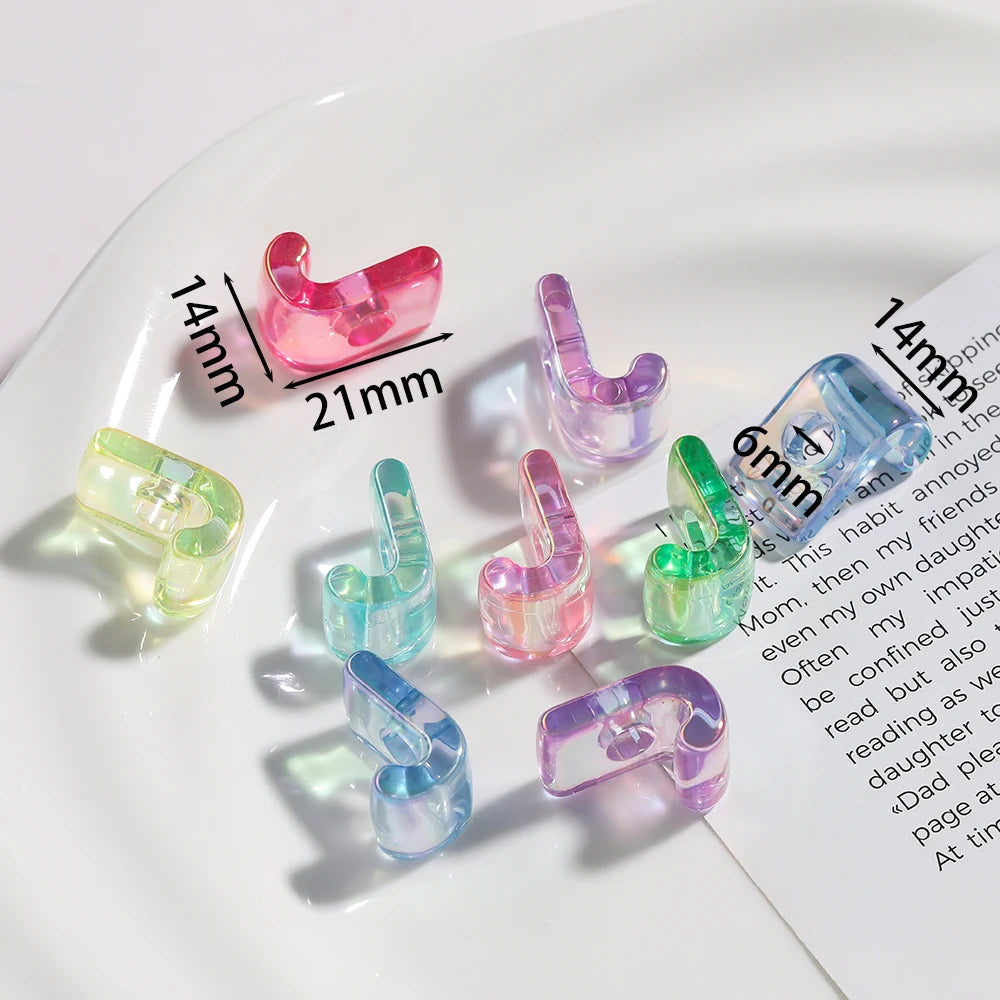 A collection of pink and clear acrylic alphabet beads displayed on a white plate with measurement lines.