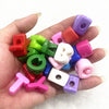 A hand holds a collection of 10 mixed alphabet letter beads in various colors and shapes for DIY jewelry making