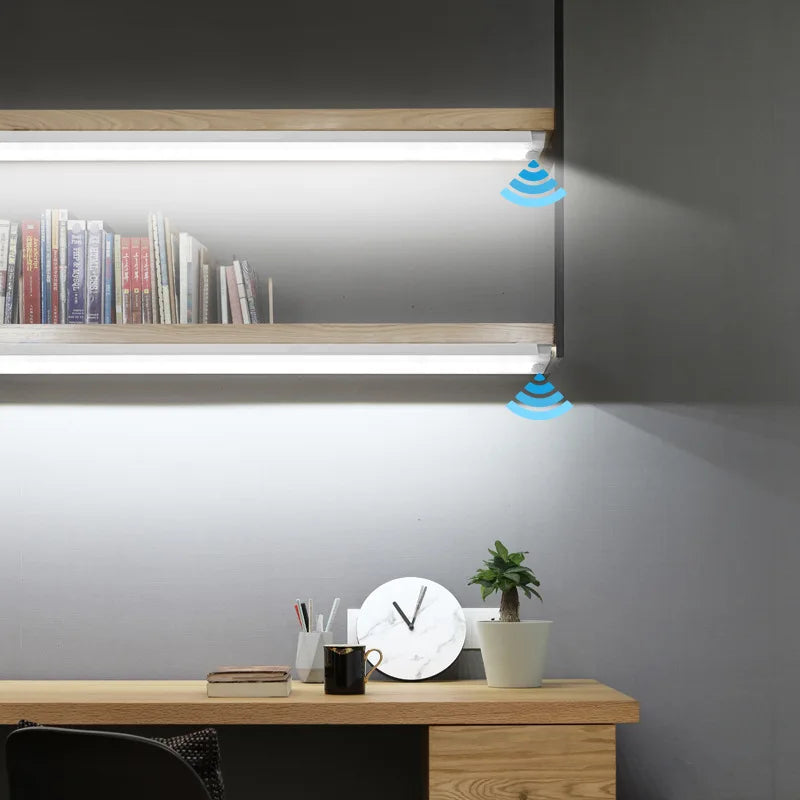 A modern desk setup featuring a wooden shelf with illuminated LED cabinet lights and a potted plant.