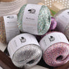 Three spools of glitter yarn in various shades including silver, pink, and green with labels