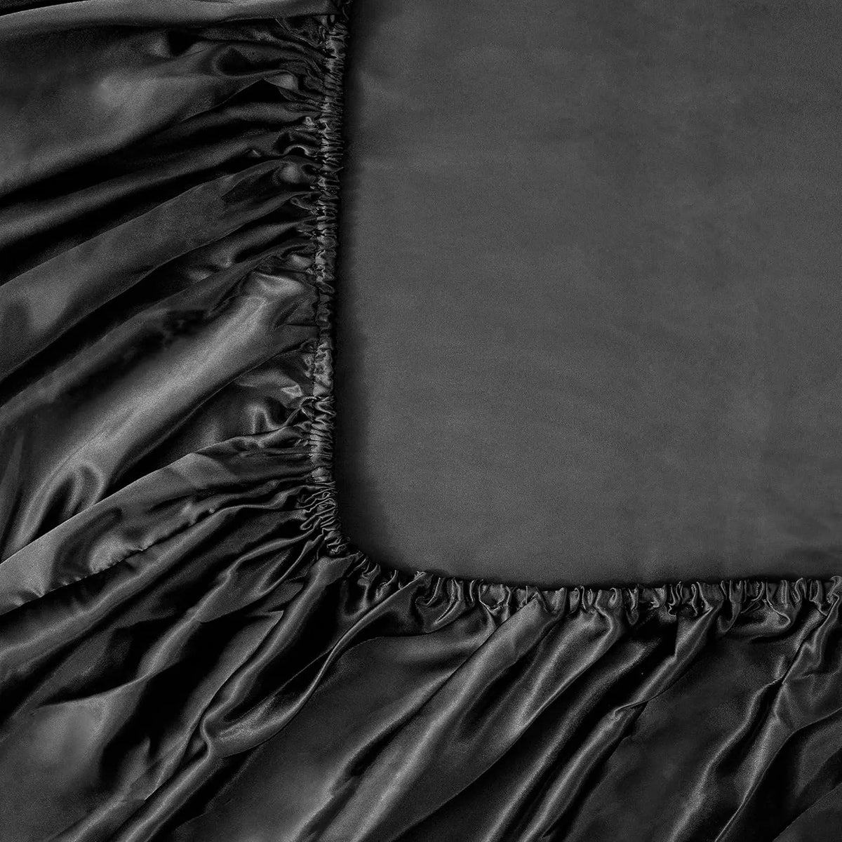 A close-up of dark satin fabric draped and gathered, showing luxurious texture and folds.